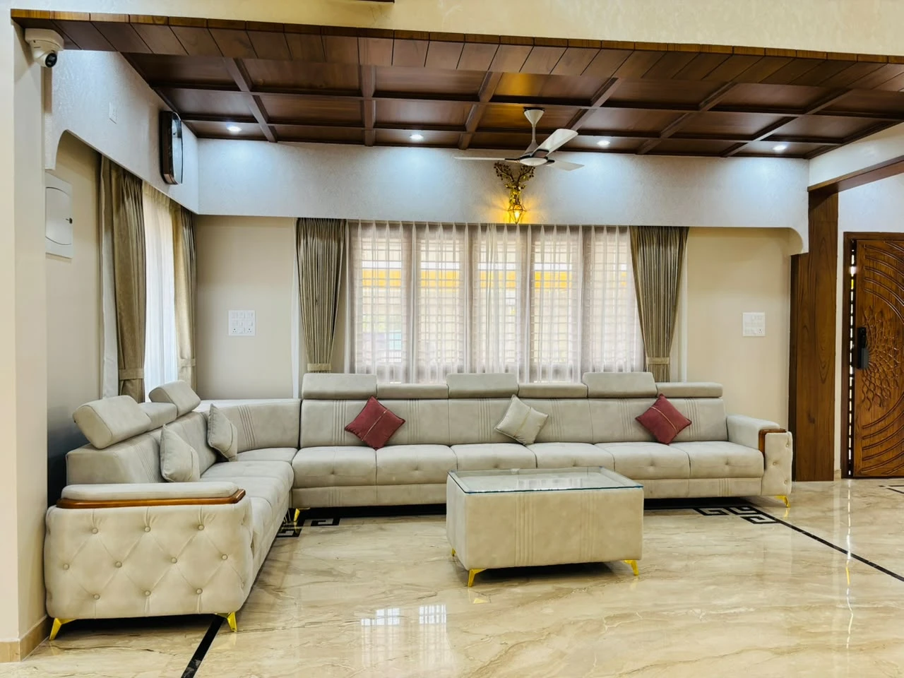 Cream L-shaped sofa, layered curtains and a timber ceiling in a furnished living room
